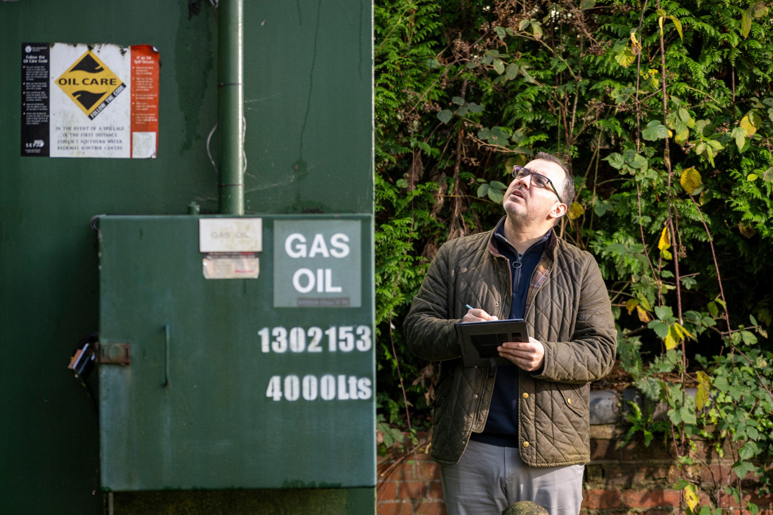 Bressummer A.R.K's Jon taking notes next to a large, outdoor electrical generator as part of a planned preventative maintenance survey