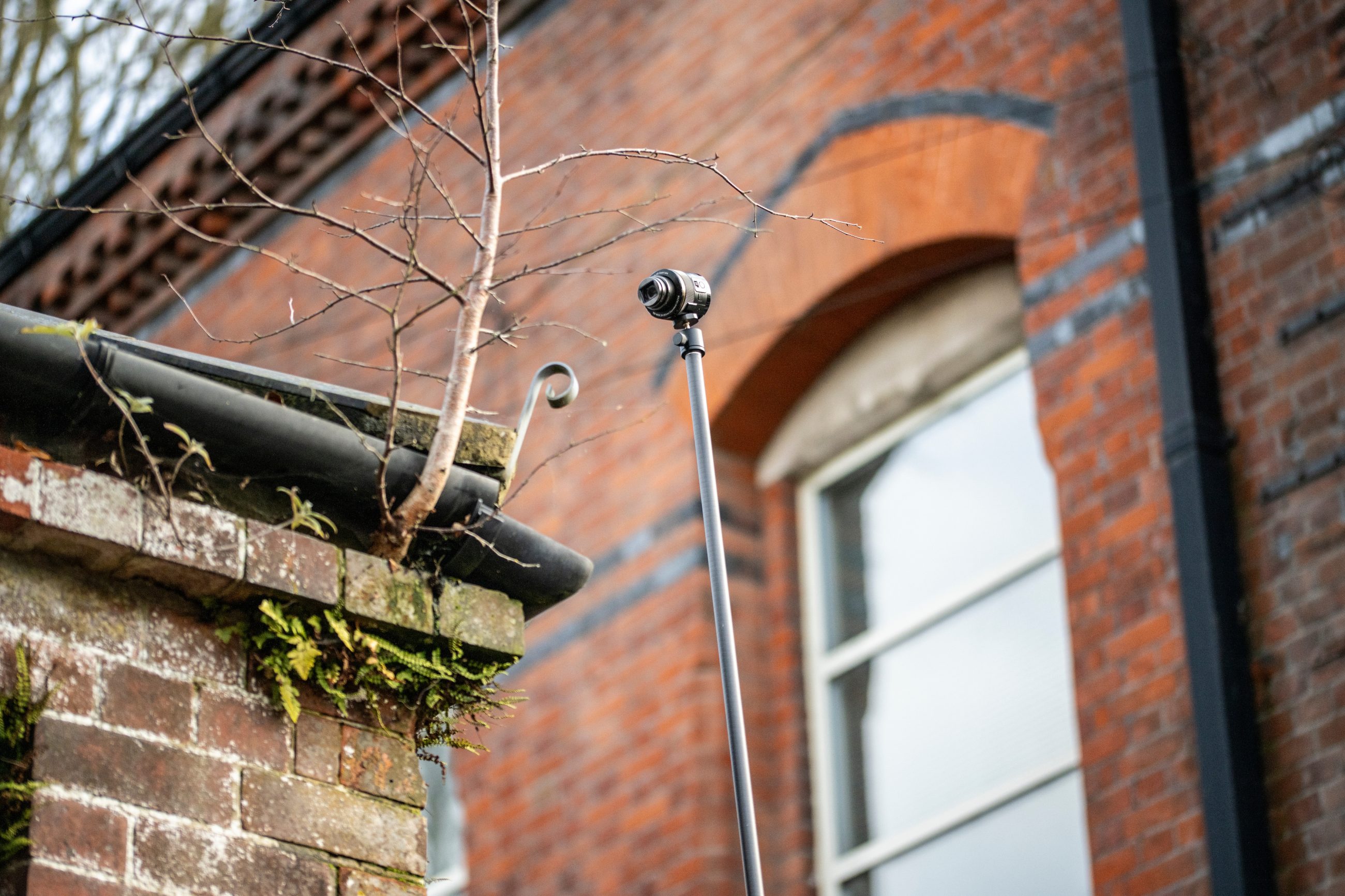 A telescopic pole camera taking photos of the roof or an older building as part of a full building survey