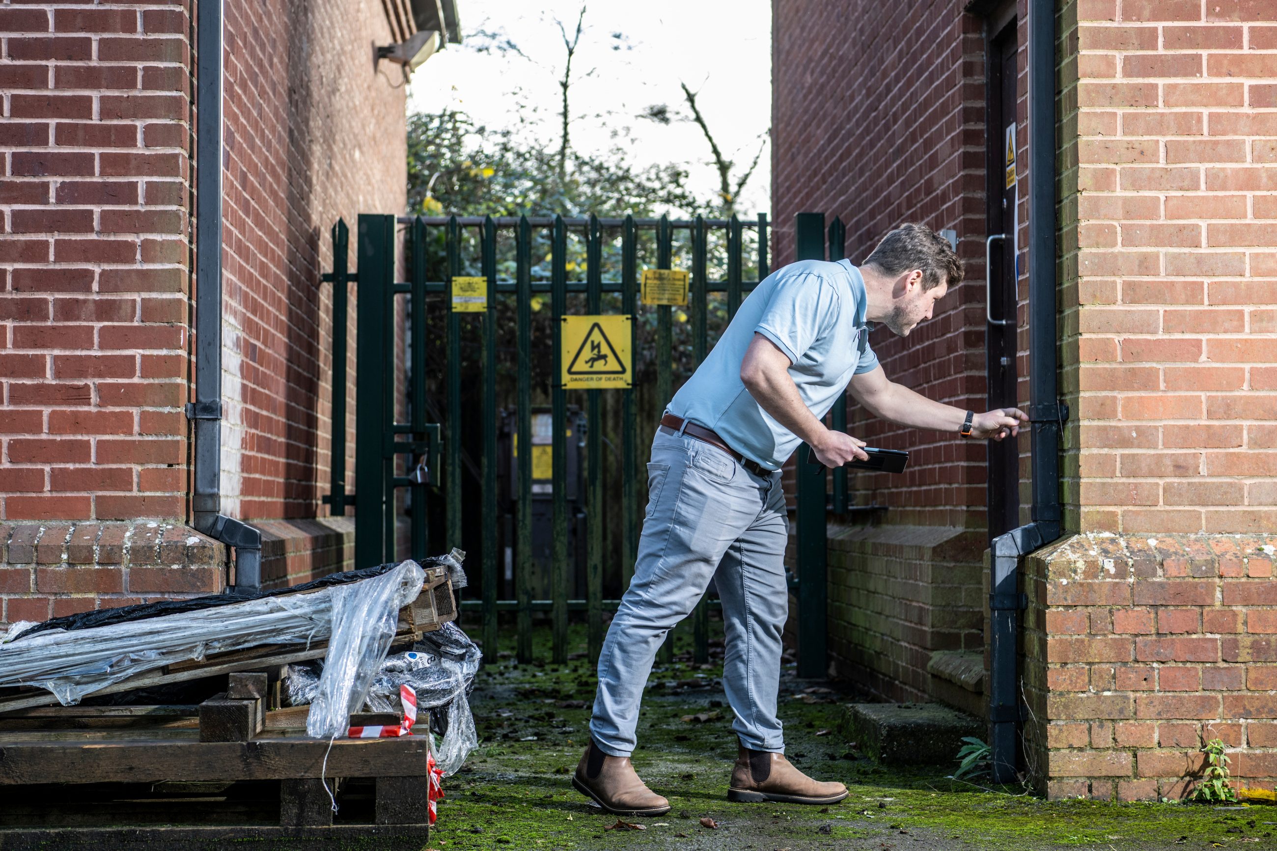 RICS surveyor inspecting a drainpipe on a commercial building in Portsmouth, for a schedule of condition report.
